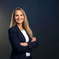 Simone Fortier standing with her arms crossed, wearing a navy blazer and white blouse.